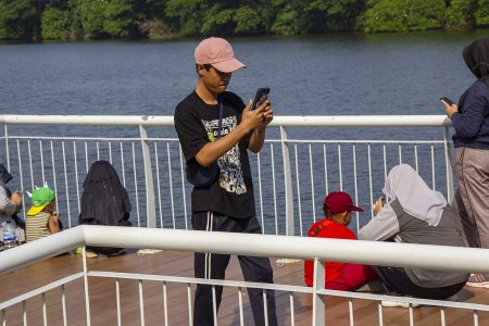 A person using a smartphone beside a lake